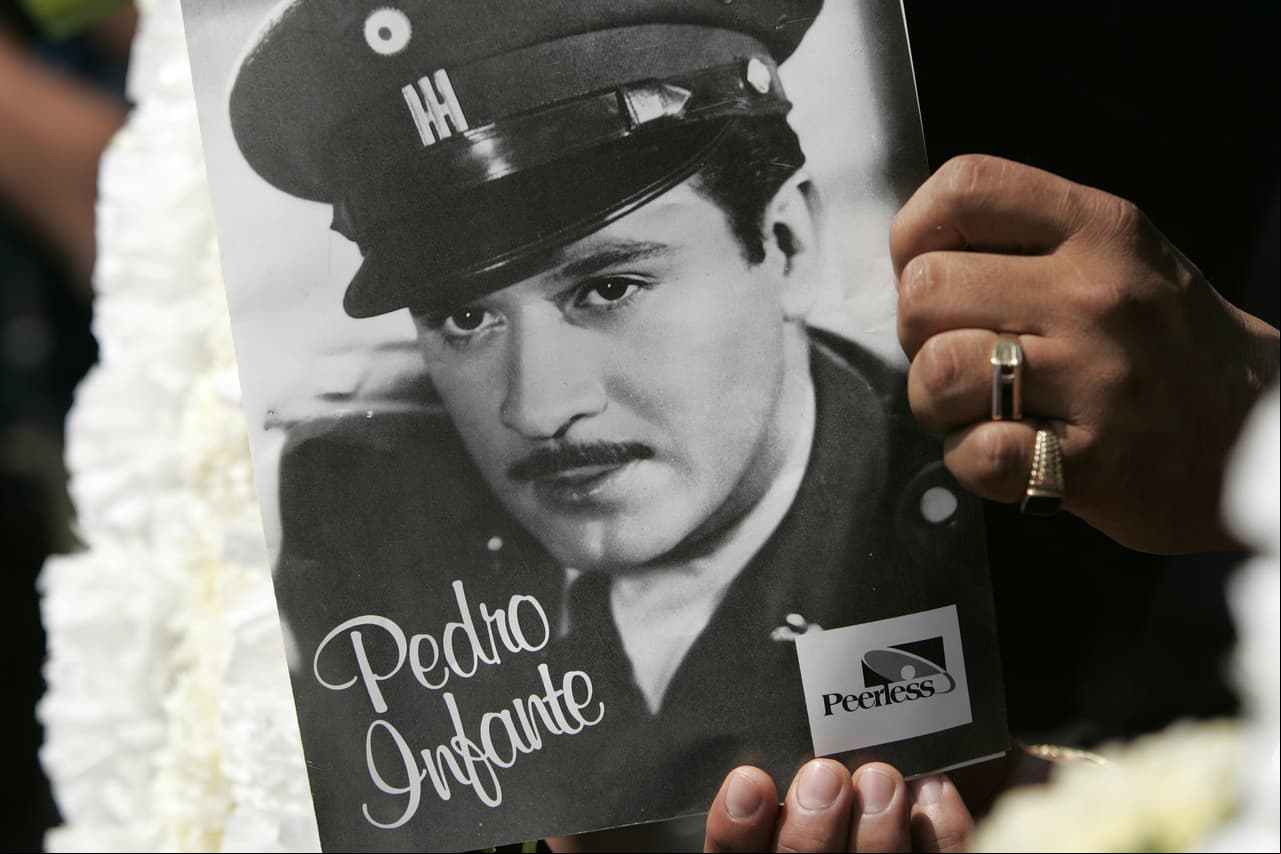 Una mujer sostiene una foto de Pedro Infante mientras visita su tumba