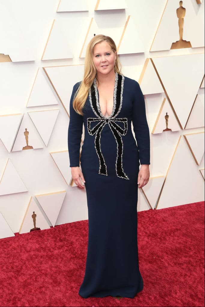 Amy Schumer impactó con un vestido azul marino con corte sirena y pronunciado escote, mismo que tenía un elegante detalle don forma de lazo rodeado en cristales.