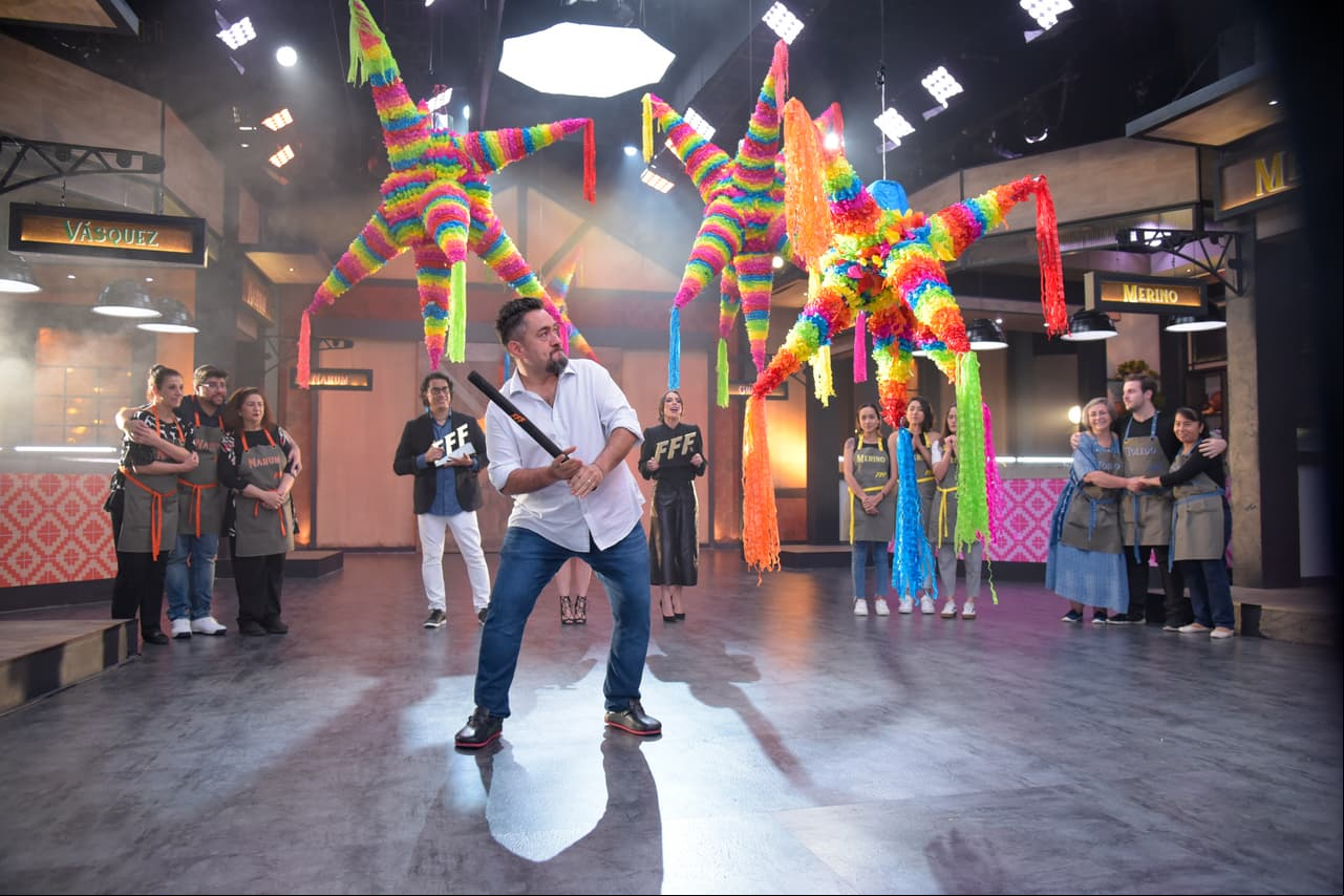 Toño debía golpear la piñata, que en su interior, contenía en color de la cocina ganadora.