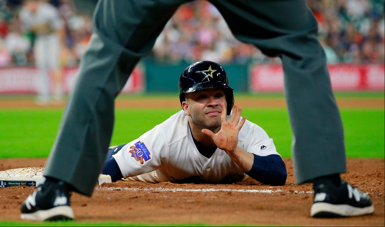 José Altuve llega a primera base y le hace la señal al umpire Dan Bellino en un juego contra los Oakland Athletics.