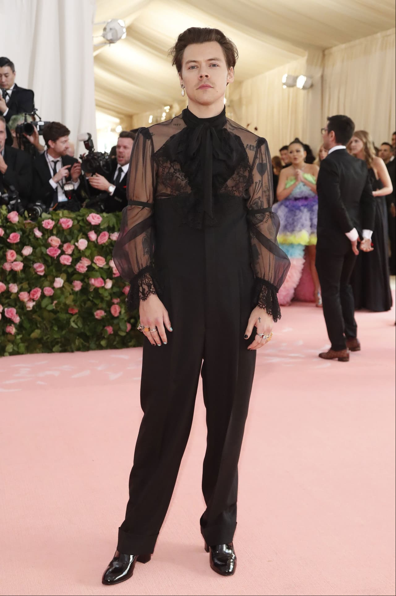 El cantante Harry Styles optó por una blusa transparente y pantalones negros, además de añadir a su look un arete, de Gucci.
