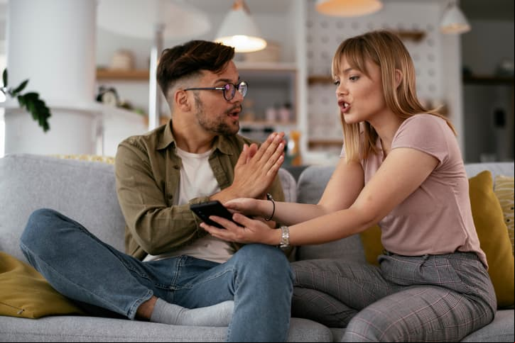 Boyfriend and girlfriend are arguing on the couch. Angry woman is yelling at her boyfriend.